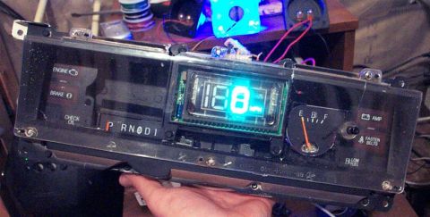 1985 Ford Crown Victoria LTD - A car's dashboard gauge cluster is held, showing a digital display and various warning lights.