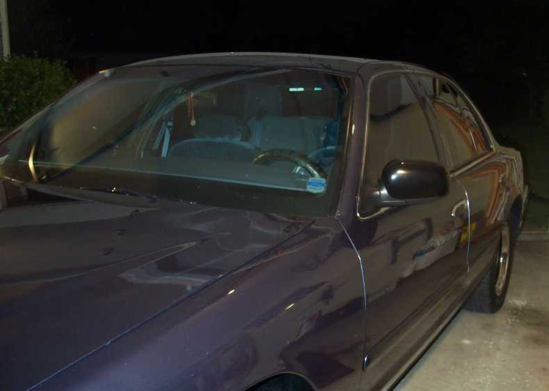 Night view along the polished driver's side and hood of a dark Ford sedan