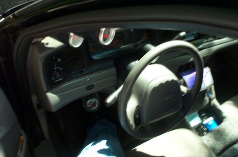 1999 Ford Crown Victoria - The interior of a car is shown, a steering wheel and additional gauges mounted on the dashboard.