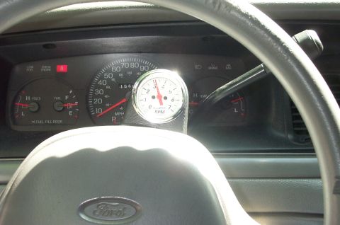 1999 Ford Crown Victoria - The interior of a 1999 Ford Crown Victoria shows the dashboard with a tachometer and the Ford logo on the steering wheel.