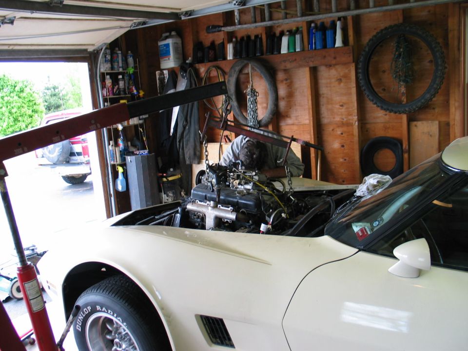 White 1981 Chevrolet Corvette with engine being removed by an engine hoist