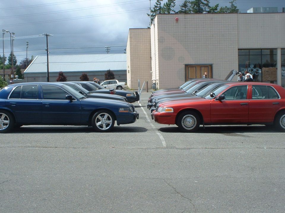 Side view of blue and red 1999 Ford Crown Victorias parked head-to-head