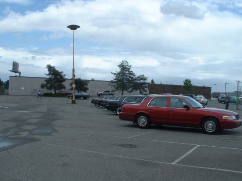 1999 Ford Crown Victoria - A red 1999 Ford Crown Victoria is parked in a lot alongside other vehicles under a cloudy sky.