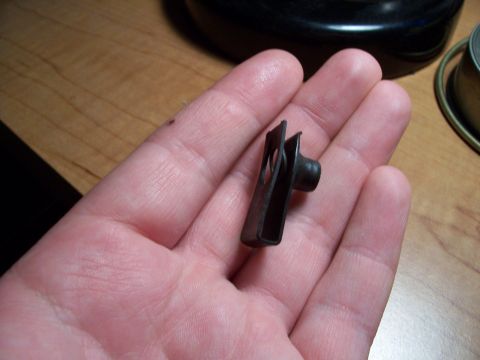 1995 Ford Bronco - A single black hard top clip is held in a person's palm, with a wooden surface in the background.