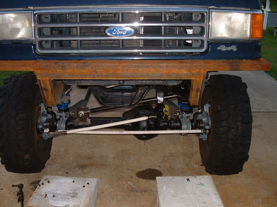 Front underside of blue Ford 4x4 showing solid axle, tie rods and large tires