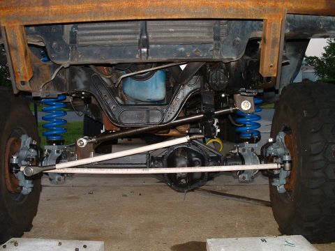 1995 Ford Bronco - Underside view of modified front axle and suspension components with large tires visible.