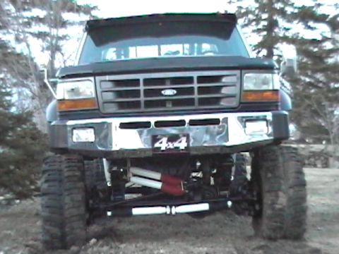 1979 Ford Bronco - This black Ford F-series truck features a prominent 4x4 badge on the front bumper and appears to be lifted with large off-road tires.