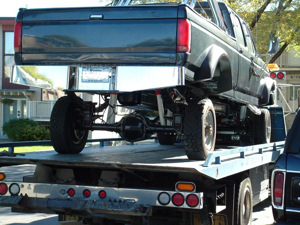 Dark blue 1992 Ford F-350 Crew Cab truck on a flatbed tow truck, rear view