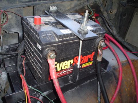 1981 Ford Bronco - A black EverStart maintenance-free battery clamped into a fabricated steel tray with an aluminum hold-down bar and threaded J-hooks, wired…