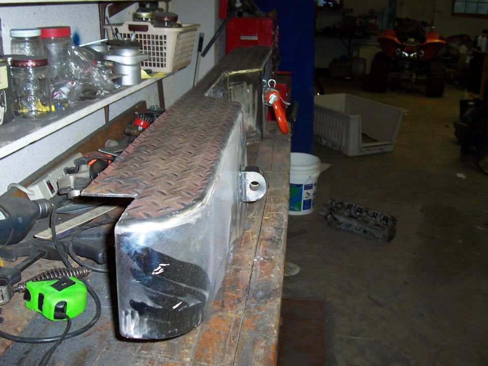 Custom diamond plate metal bumper on a workbench, with tools and shelves in background