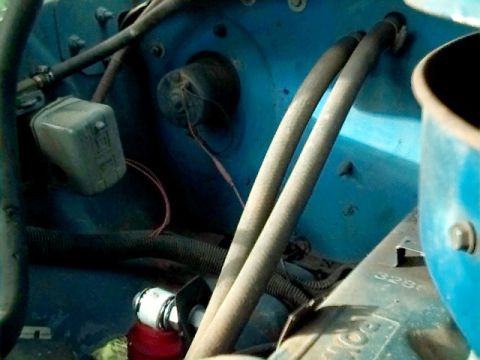 1978 Ford Bronco - Close-up view of engine bay components, including hoses and an electrical box, against a blue firewall.