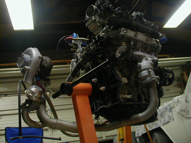 Engine on an orange stand with a turbocharger and exhaust manifold
