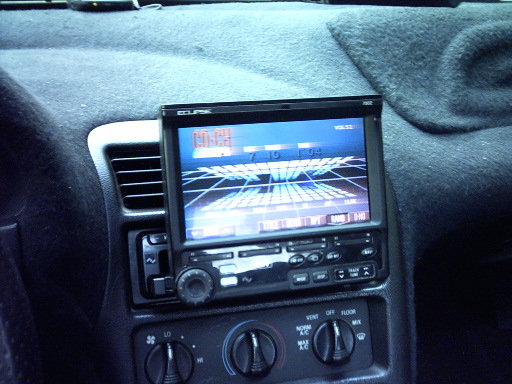 Aftermarket Eclipse flip-out screen stereo above factory tape deck in a carpeted dash center stack