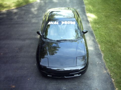 1995 Ford Probe - This black car has a custom windshield banner that reads "ANAL PROBE".