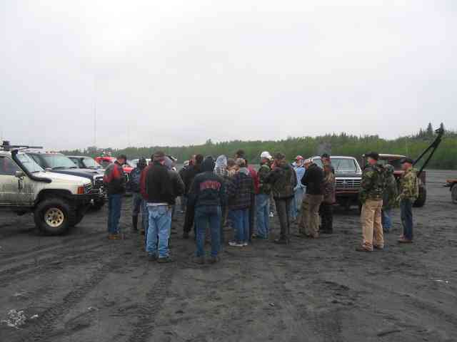 Group of people at an off-road trail-ride driver's meeting surrounded by lifted 4x4s