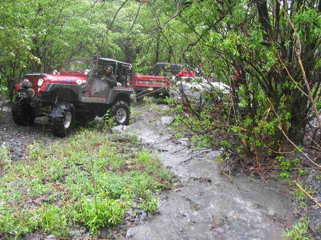 Red off-road vehicle with large tires on a muddy trail