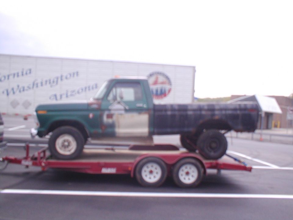 Ford F-Series pickup on a trailer. Truck is green and white with a black bed