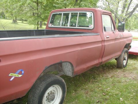 1979 Ford Bronco - Side view of a red pickup truck, likely a 1979 Ford F-Series, parked on grass.