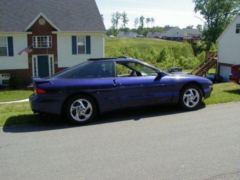 1994 Ford Probe - A blue 1994 Ford Probe coupe is parked on a street in front of a residential house.