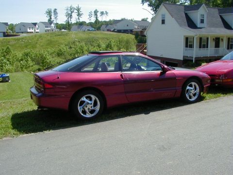 1994 Ford Probe - Side profile of a red 1994 Ford Probe parked on a residential street.