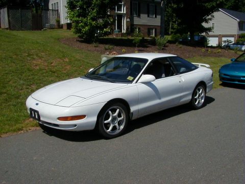 1994 Ford Probe - A white 1994 Ford Probe is parked on a residential street next to a teal car.