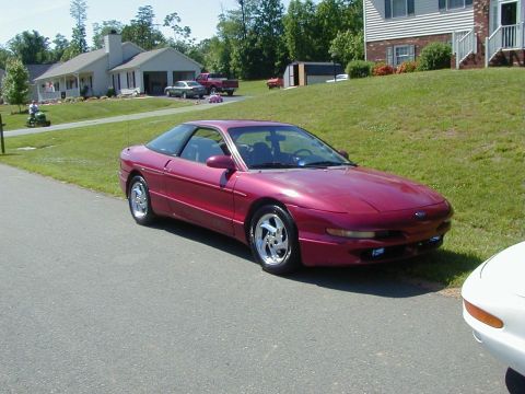 1994 Ford Probe - A red 1994 Ford Probe is parked on a suburban street next to a white car.