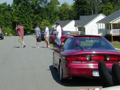1994 Ford Probe - A red 1994 Ford Probe is parked on a street with several people standing around.