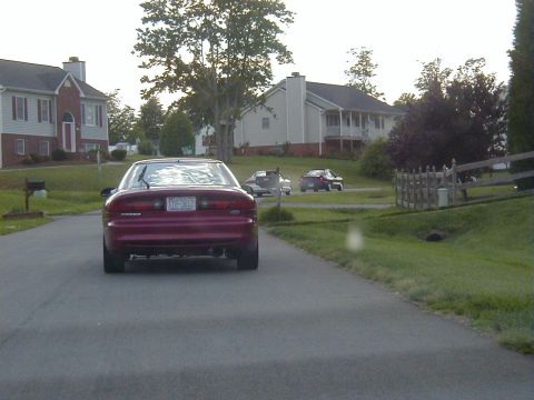 1994 Ford Probe - A red 1994 Ford Probe is seen from behind on a residential street, with other vehicles in the background.