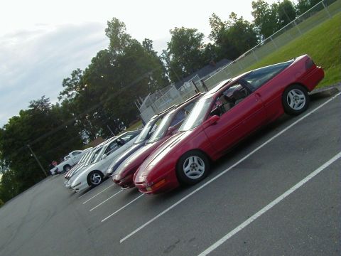1994 Ford Probe - Multiple coupes are parked in a lot, with one red coupe prominently in the foreground.