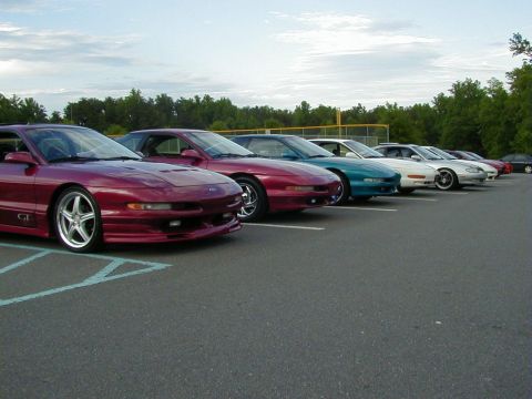 1994 Ford Probe - A line of Ford Probes are parked in a lot under a cloudy sky.