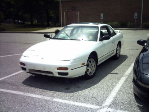 1995 Ford Probe - A white coupe is parked in a lot next to another vehicle.