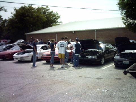 1995 Ford Probe - Several cars are parked in a lot with their hoods open, as people stand around them.