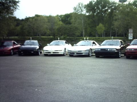 1995 Ford Probe - Several cars are parked in an asphalt lot with trees in the background. The website "SUPERMOTORS.NET" is visible at the bottom right.