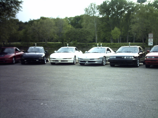 six cars parked in a lot, including a red one, black one, two white ones, and a black one