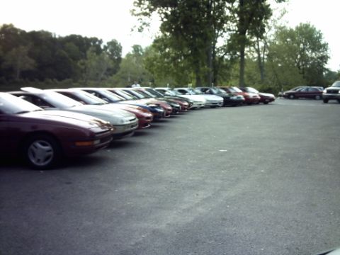 1995 Ford Probe - A row of Ford Probe cars are parked in a lot, with trees in the background.