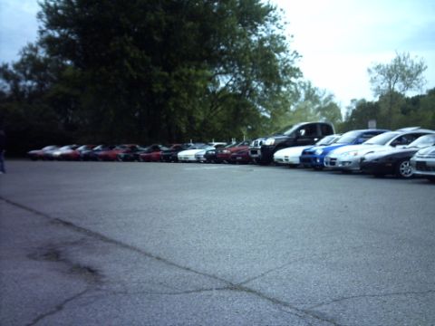 1995 Ford Probe - A collection of vehicles, including a truck and multiple sports cars, are parked in a lot under an overcast sky.