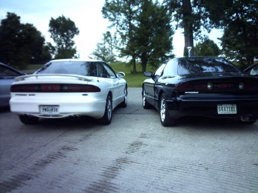 Two 1995 Ford Probe cars, one white and one black, parked on pavement