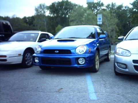 1995 Ford Probe - A blue Subaru Impreza WRX is parked between a white car and a silver car.