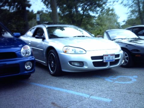 1995 Ford Probe - A silver coupe is parked between a blue car and a black car, with a blue license plate visible on the front.