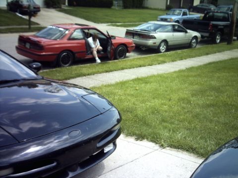 1995 Ford Probe - A black 1995 Ford Probe is parked in the foreground, with other vehicles visible in the background.