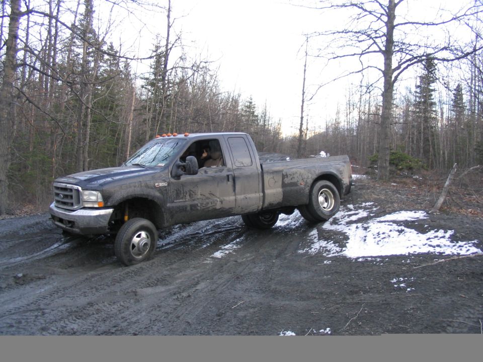 Dark 2002 Ford F-350 pickup truck with dual rear wheels on a dirt road