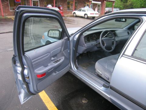2001 Ford Crown Victoria - The interior of a light blue 2001 Ford Crown Victoria is visible with the driver's door ajar.