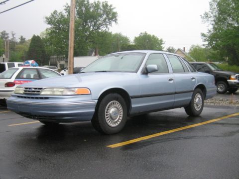2001 Ford Crown Victoria - Side view of a light blue 2001 Ford Crown Victoria parked in a lot on a rainy day.