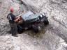 1985 Toyota 4Runner - A person stands beside a dark off-road vehicle positioned on a steep, rocky slope.
