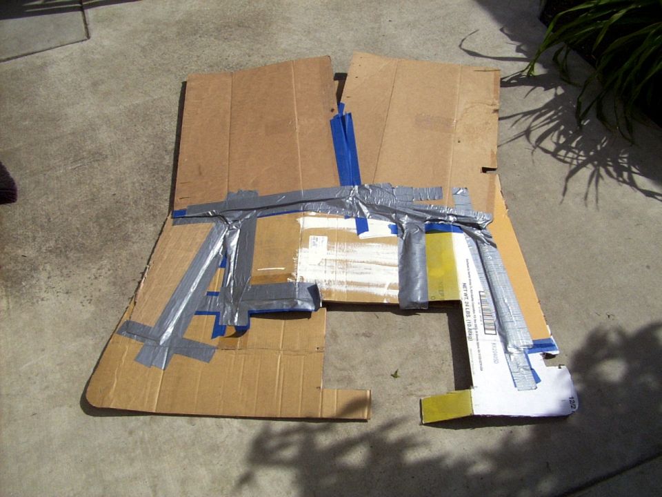 Cardboard cutout taped together, looks like a rough shape of a car part