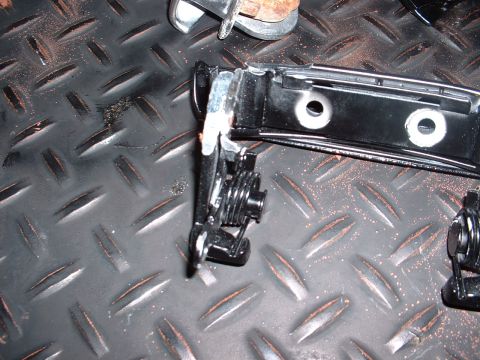 1978 Ford Mustang II - Close-up of a car door latch mechanism, showing its internal components and spring assembly on a textured metal background.
