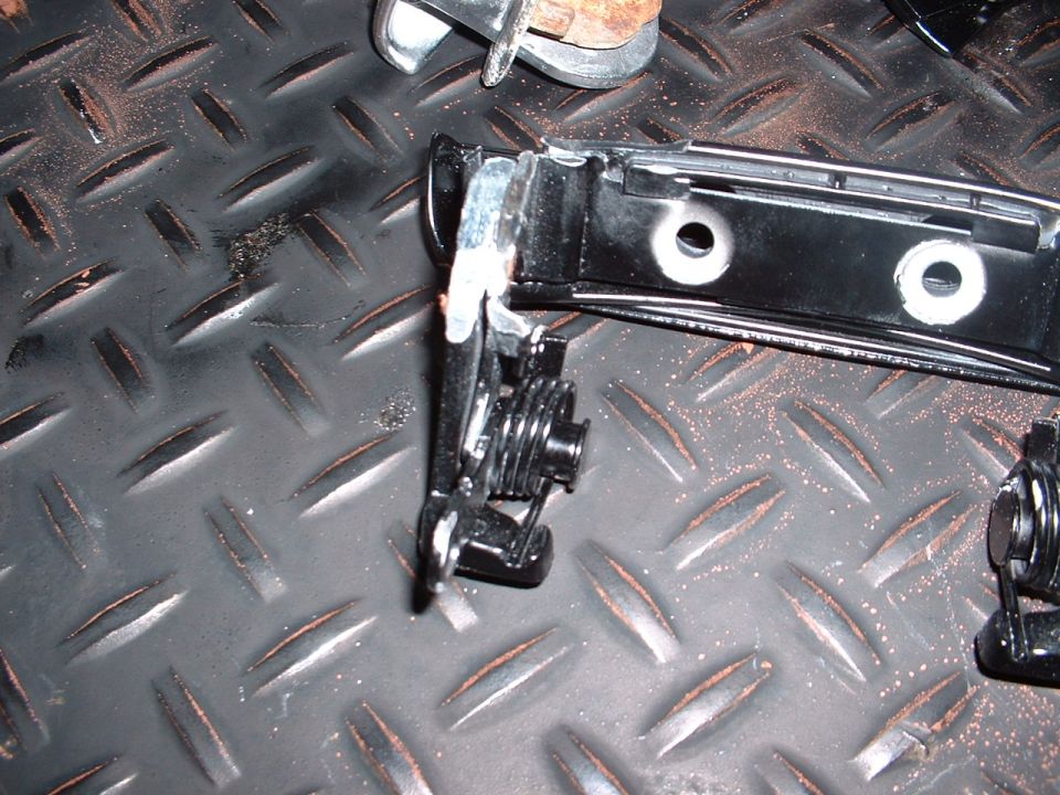 Car door latch mechanism with spring and metal components on a diamond plate surface