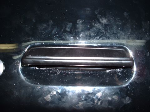 1978 Ford Mustang II - Close-up of a black car door handle with chrome trim, showing some wear and dust.