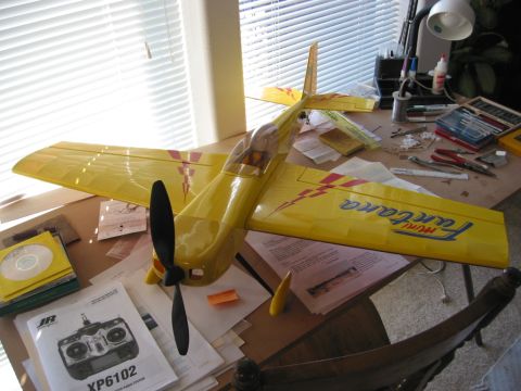 1991 Ford Explorer - A yellow model airplane sits on a desk covered in papers and hobby supplies, including an RC transmitter manual.