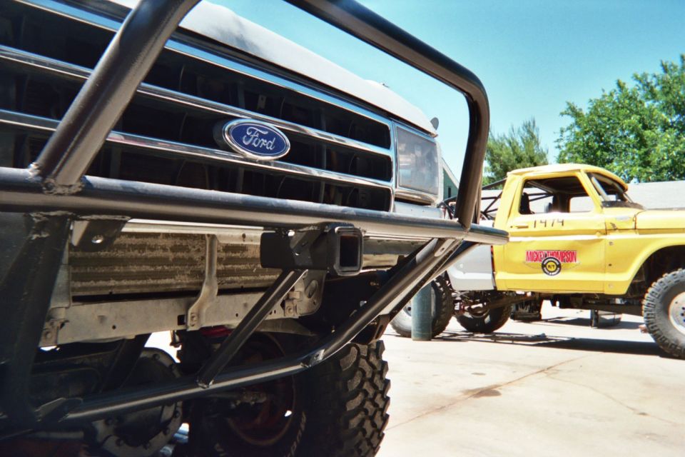 Ford grille emblem behind a tube bumper with a yellow truck behind